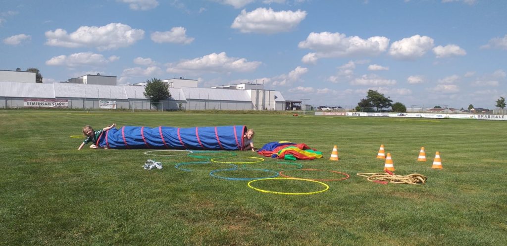 Das Bild Kinder beim Turnen auf einer Wiese